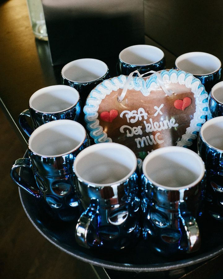 Blue mugs with the “PSA × Der kleine MUC” gingerbread heart